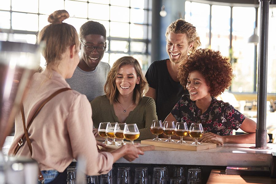 Specialized Business Insurance - Waitress Serving a Happy Group Of Friends Beer Tasting In a Local Brewery